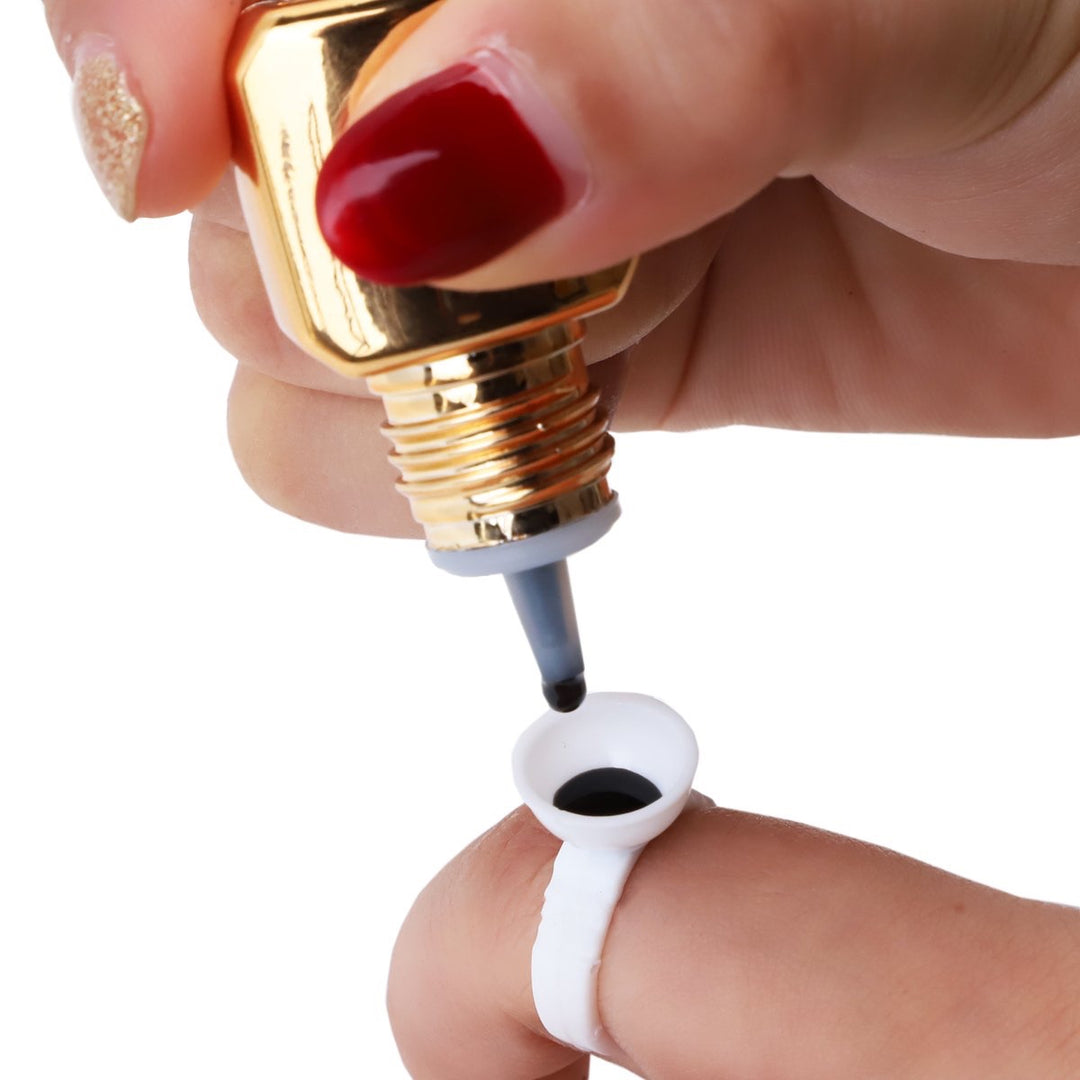 Eyelash extension glue being dispensed onto a ring. Professional lash adhesive for easy application.
