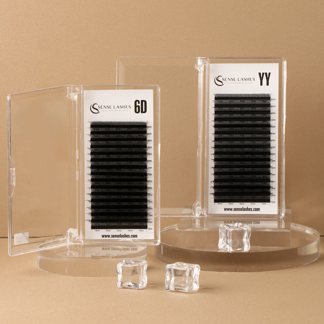 Two clear containers of black eyelash extensions are displayed on clear circular stands.