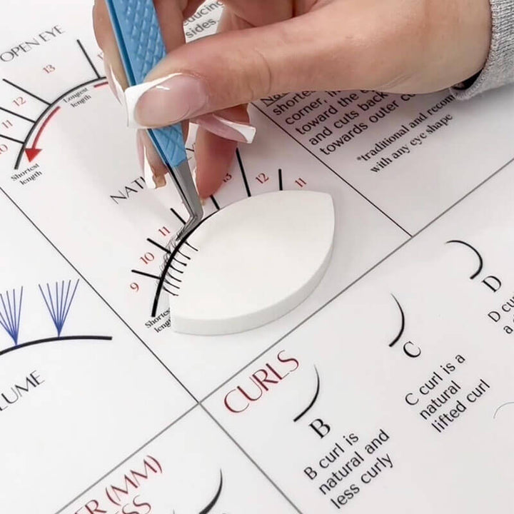 Lash artist practicing lash extension technique on eye-shaped foam sponge