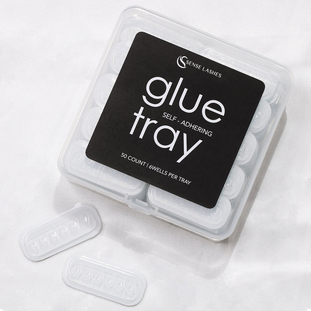 A clear plastic tray with black label reading "glue tray" by Sense Lashes, containing 50 self-adhering wells.