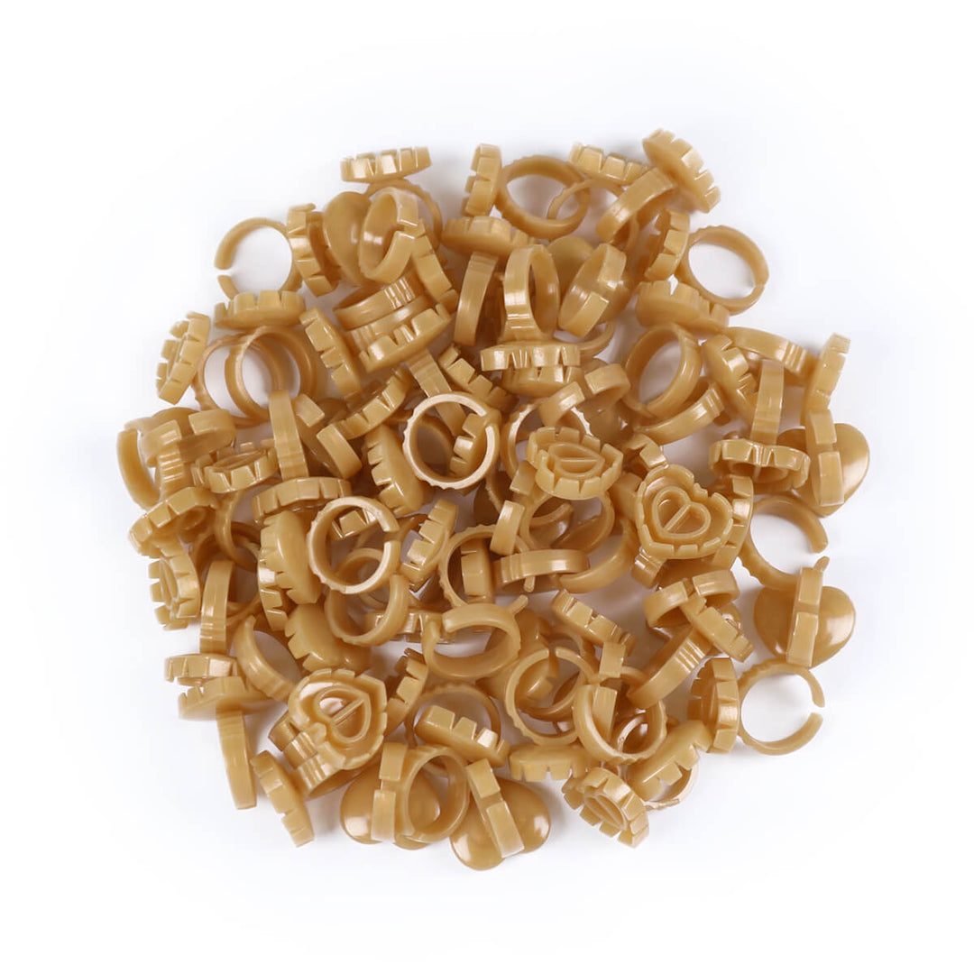 A pile of beige Sweet Heart Glue Cups scattered on a white background.