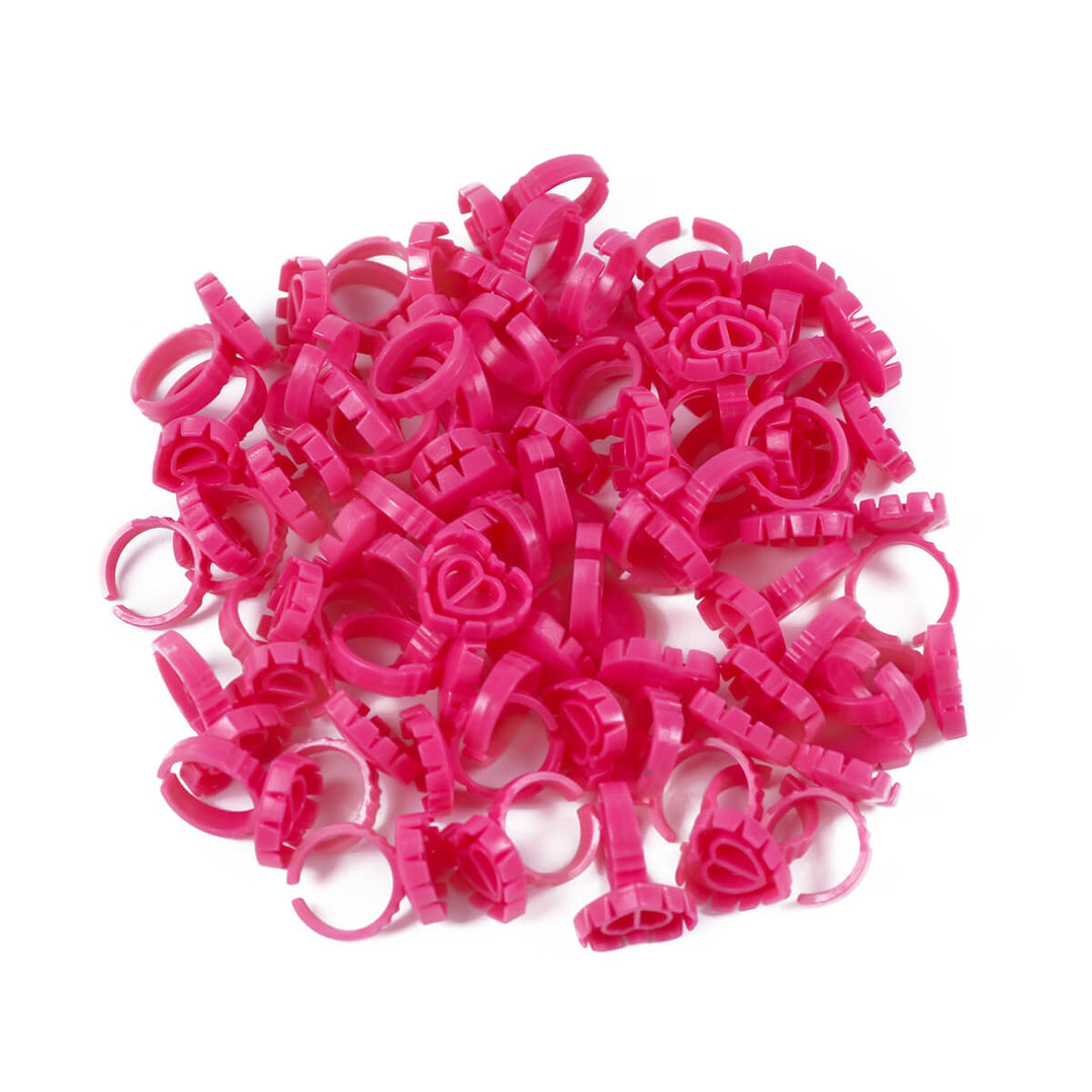 A pile of pink Sweet Heart Glue Cups for eyelash extensions, neatly arranged on a white background.