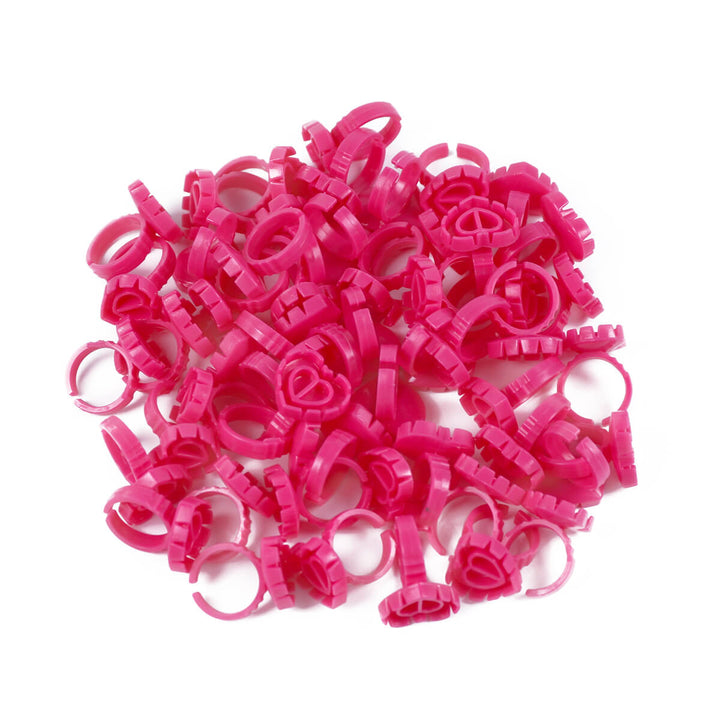 A pile of pink Sweet Heart Glue Cups for eyelash extensions, neatly arranged on a white background.
