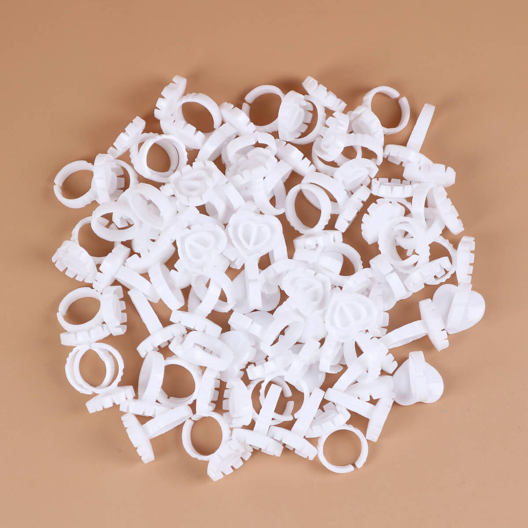 A pile of white Sweet Heart Glue Cups scattered on a brown background.